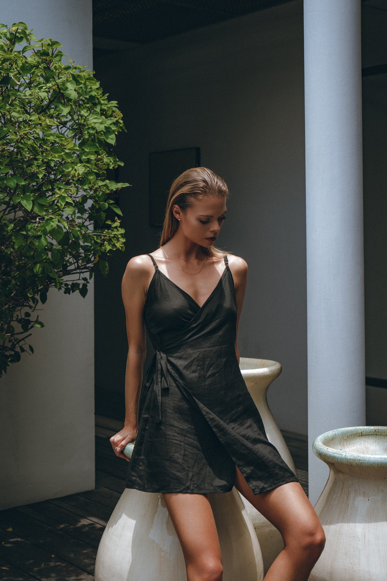 a girl in a linen summer wrap dress standing in a beautiful garden 